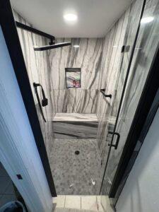 a marble walk in shower with mosaic tiles