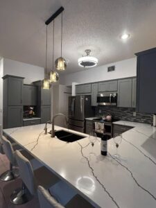 a contemporary kitchen with white and black. There is a undermount sink with new lighting throughout
