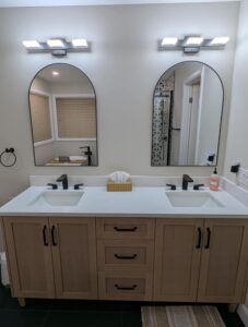 Wood double vanity with lights and mirrors in a remodeled bathroom