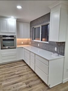 New kitchen with wood floors, gray tile, and white countertops