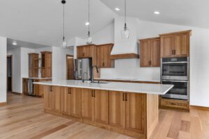 new kitchen with wood cabinets open concept. there are wood floors and white countertop fully custom