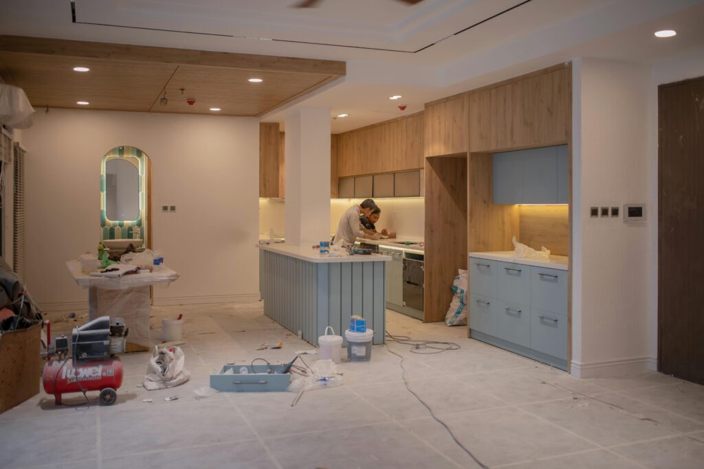 pexels-photo-15124970-15124970 A modern kitchen undergoing renovation, featuring a worker, tools, and materials.