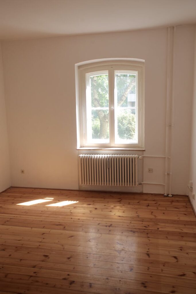 pexels-photo-3125905 Spacious empty room with wooden floor and large window in Berlin, ideal for interior planning.